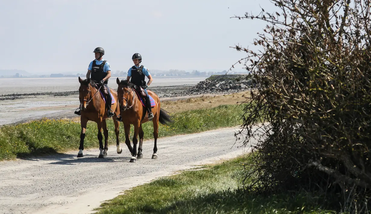 Polisi berkuda berpatroli dekat pantai selama lockdown nasional untuk melawan virus corona COVID-19 di Cancale, Prancis, Sabtu (11/4/2020). Prancis masuk periode lockdown pada pertengahan Maret lalu. (AP Photo/David Vincent)