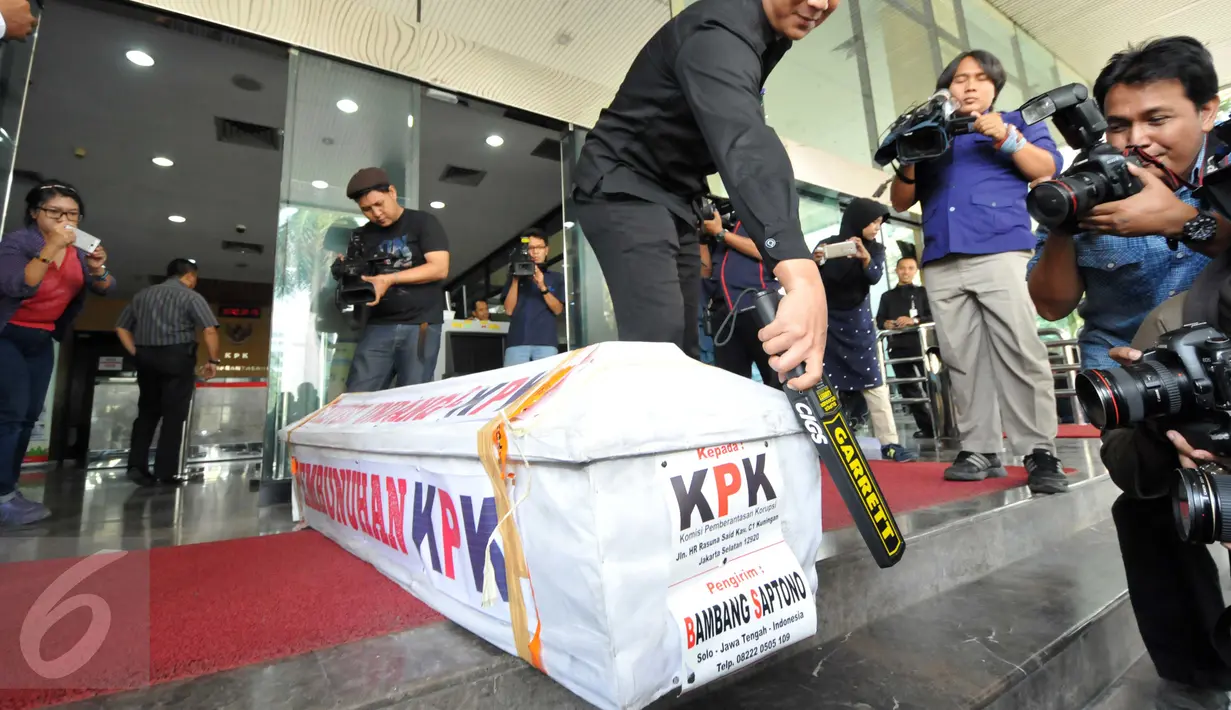 Petugas keamanan memeriksa sebuah peti mati bercat putih di Gedung KPK, Jakarta, Selasa (20/10). Peti yang bertuliskan "Revisi UU KPK, Pembunuhan KPK" itu dikirim oleh Bambang Saptono, warga Solo, Jawa Tengah. (Liputan6.com/Helmi Afandi)