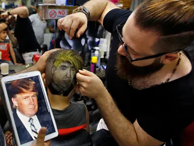 Tukang cukur rambut, Muhannad Khaled Omar membuat lukisan bergambar Donald Trump dikepala pelanggannya di Burj al-Barajneh, Lebanon (14/7). Omar adalah penata rambut yang terkenal membuat lukisan di kepala pelanggannya.  (AP Photo / Bilal Hussein)