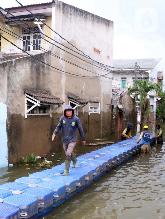 Petugas membuat jembatan apung saat banjir melanda Perumahan Periuk Damai, Tangerang, Banten, Selasa (23/2/2021). Adanya jembatan apung mempermudah warga saat melintasi banjir setinggi 2,5 meter di tempat tersebut. (Liputan6.com/Angga Yuniar)