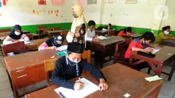 Guru mengawasi murid kelas V saat menjalani ujian Penilaian Akhir Semester (PAS) tahun pelajaran 2020/2021 di Madrasah Ibtidayah (MI) Assu'ada di Pancoran Mas, Depok, Jawa Barat, Selasa (1/12/2020). Ujian dilaksanakan dengan menerapkan protokol kesehatan dalam kelas. (merdeka.com/Arie Basuki)