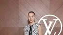 Phoebe Dynevor mengenakan mini dress warna hitam putih dengan aksen pita panjang warna hitam senada dengan warna mini bag dan knee boots leather nya.  [dok. Louis Vuitton]