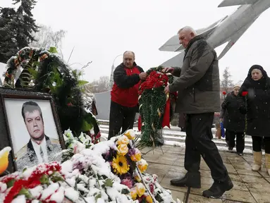 Warga meletakkan karangan bunga di dekat potret pilot asal Rusia, Oleg Peshkov di Lipetsk, Rusia, Rabu (2/12). Oleg Peshkov adalah pilot yang tewas saat pesawat tempur Su-24 yang dikemudikannya ditembak jatuh Turki pekan lalu. (REUTERS/Maxim Zmeyev)