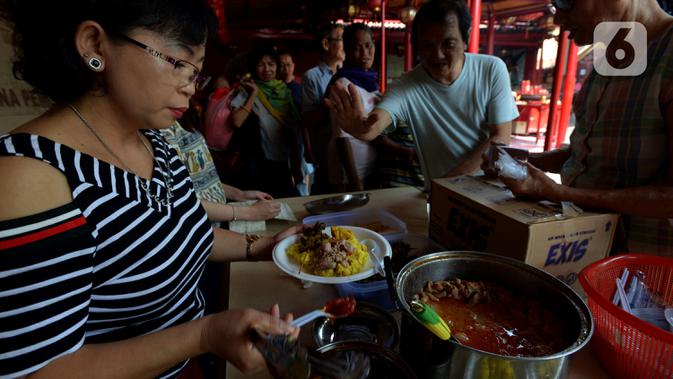 Pengurus Vihara Kim Tek Ie menyiapkan menu makan siang untuk pembeli warung nasi kuning Podjok Halal di Petak Sembilan, Jakarta, Selasa (24/12/2019). Warung ini merupakan cabang kesembilan sejak didirikan pada 6 Febuari 2018 lalu. (merdeka.com/Imam Buhori)