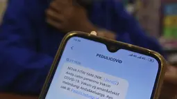 Tenaga kesehatan membaca pesan singkat penerima vaksin COVID-19 di RSIA Tambak, Jakarta, Selasa (5/01/2021). Kementerian Kesehatan mengirimkan Short Message Service (SMS) blast secara serentak kepada penerima vaksin COVID-19 tahap pertama pada Kamis (31/12) lalu. (Liputan6.com/Herman Zakharia)