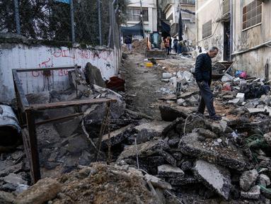 Warga Palestina berjalan setelah penyerbuan militer Israel ke kamp pengungsi Nur Shams di Tepi Barat, Rabu 27 Desember 2023. (AP Photo/Majdi Mohammed)