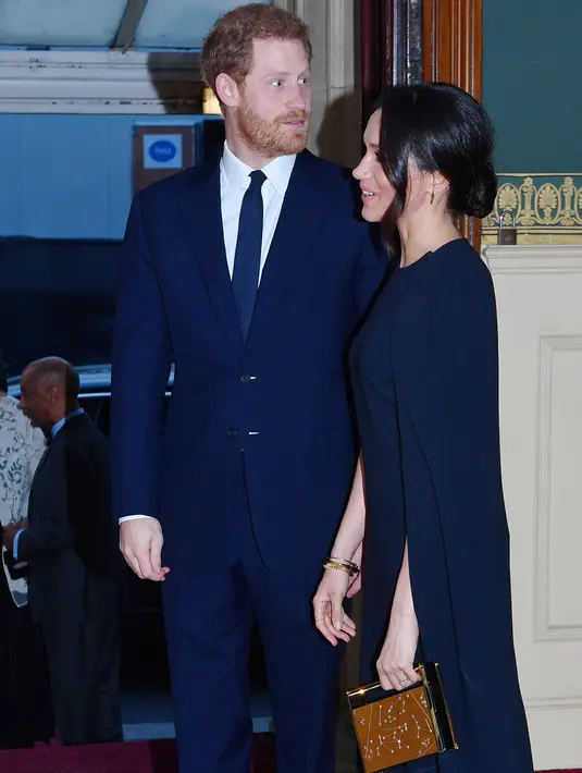 Pangeran Harry bersama tunangannya, Meghan Markle menghadiri konser perayaan ulang tahun Ratu Elizabeth di London, Sabtu (21/4). Di tangannya, Meghan memakai clutch box dari Naeem Khan dengan motif perbintangan. (ANDREW PARSONS/POOL/AFP)