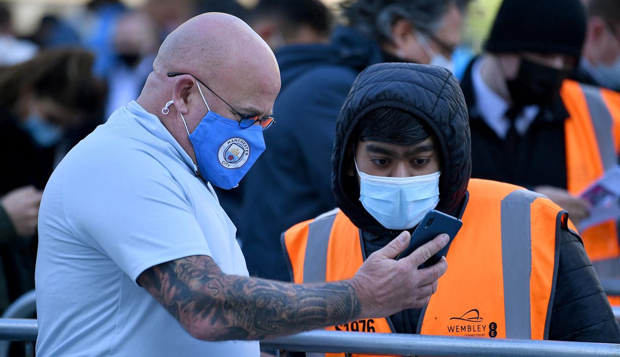 Penonton dengan memakai masker memberikan bukti tes virus corona negatif kepada petugas sebelum pertandingan dimulai. (Foto: AFP/Pool/Ben Stansall)
