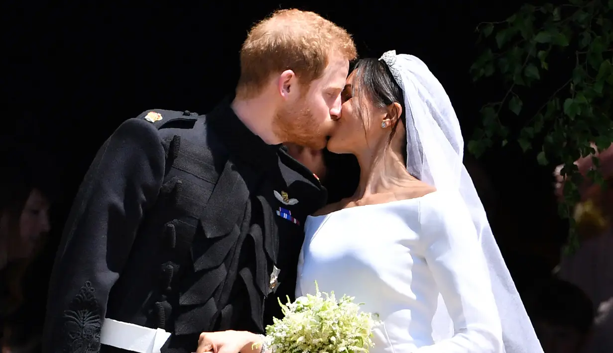 Pangeran Harry mencium istrinya, Meghan Markle di tangga Pintu Barat St George's Chapel, Kastil Windsor, Inggris, Sabtu (19/5). Pangeran Harry dan Meghan Markle telah resmi menikah. (Ben STANSALL/POOL/AFP)