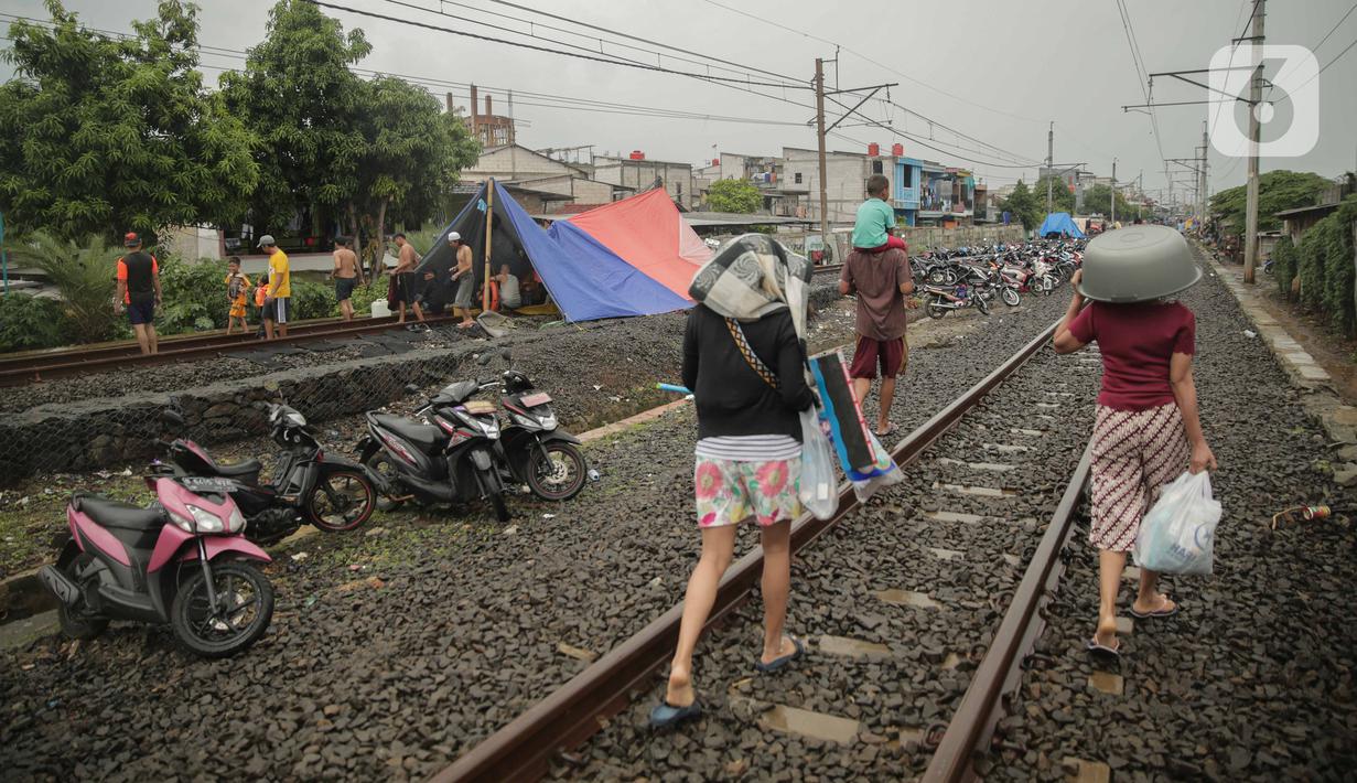 Tenda pengungsi banjir didirikan di jalur rel kereta commuterline Tangerang-Duri di Kembangan Baru, Jakarta, Jumat (3/1/2020). Jalur rel yang nonaktif sementara karena banjir dimanfaatkan warga sekitar untuk mendirikan tenda darurat karena rumah mereka masih terendam. (Liputan6.com/Faizal Fanani)