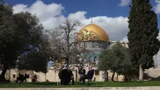 Para pria Palestina duduk di dekat Kubah Batu, kompleks Masjid al-Aqsa, Yerusalem menjelang waktu berbuka puasa selama bulan suci Ramadan 1447 Hijriah pada Rabu 25 Februari 2026. Kubah Shakhrah atau Dome of the Rock atau Qubbat as-Sakhrah merupakan ikon di kompleks Masjid Al Aqsa. (AHMAD GHARABLI/AFP)