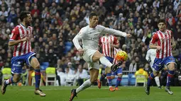 Bintang Real Madrid, Cristiano Ronaldo, mengecoh sejumlah pemain Sporting Gijon. Meski menang, Madrid masih tertahan di posisi tiga klasemen Liga Spanyol. (AFP/Pedro Armestre)