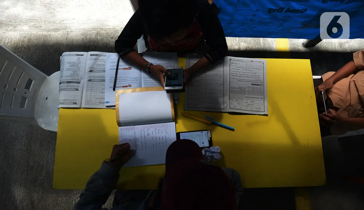 Para siswa belajar online di Tenda Wifi gratis di taman warga RT 013, Jakarta Timur, Rabu (12/8/2020). Tenda belajar tersebut menyediakan fasilitas wifi gratis bagi anak-anak sekolah yang terkendala dengan mahalnya kuota internet. (merdeka.com/Imam Buhori)