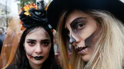 Dua orang perempuan berpose dengan dandanan menyerupai zombie ketika berpartisipasi dalam 'Zombie Walk' di pusat Kota Kiev, Ukraina, 26 Oktober 2019. Menjelang perayaan Halloween pada 31 Oktober mendatang, warga di beberapa belahan dunia sudah mulai melakukan acara bertema horor. (AP/Efrem Lukatsky)