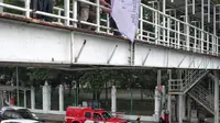 Petugas Satpol PP menertibkan alat peraga kampanye (APK) di jembatan penyeberangan orang (JPO) kawasan Gambir, Jakarta, Sabtu  (22/12). Penertiban itu dilakukan karena melanggar aturan pemasangan dari komisi pemilihan umum. (Liputan6.com/Faizal Fanani)