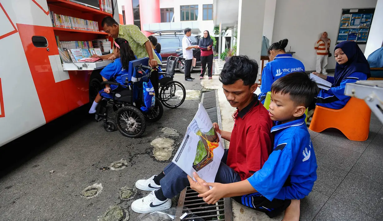 Aktivitas siswa penyandang disabilitas membaca buku pada perpustakaan keliling Sudin perpustakaan Jakarta Selatan di halaman Sekolah YPAC, jakarta, Jumat (29/11/2024). (merdeka.com/Arie Basuki)