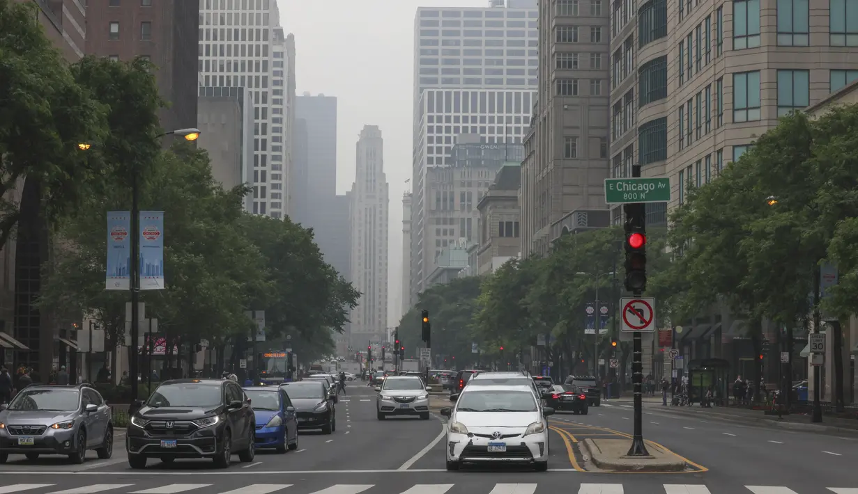 Mobil menunggu lampu merah di Michigan Avenue di bawah langit Chicago yang berkabut, Selasa, 27 Juni 2023. Kabut dari kebakaran hutan Kanada meningkatkan ozon yang lebih tinggi dan terus menciptakan kondisi jarak pandang rendah dan mengarah ke Peringatan Kualitas Udara di seluruh area. (AP Photo/Teresa Crawford)