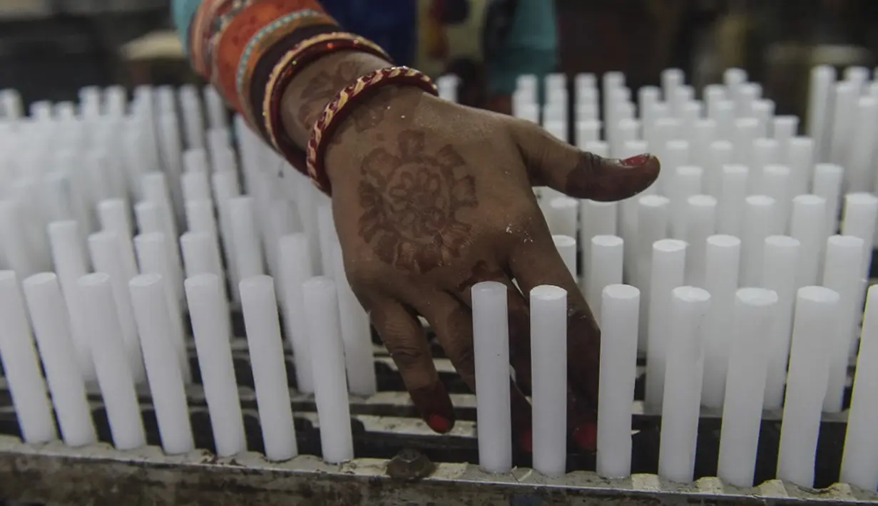 Seorang pekerja membuat lilin jelang Diwali atau Festival Cahaya di Ahmedabad, India, 25 Oktober 2021. Diwali adalah salah satu festival besar yang dirayakan oleh umat Hindu, Jain, Sikh dan beberapa umat Buddha, terutama umat Buddha Newar. (SAM PANTHAKY/AFP)