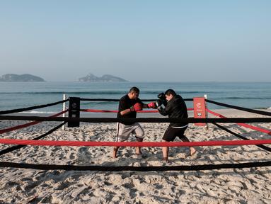  Pelatih tinju, Moacyr Lima (kiri), melatih Leandro Guignoni di ring tinju yang terletak di Pantai Pepe, Rio de Janeiro, Brasil, (26/7/2016). (AFP/Yasuyoshi Chiba)