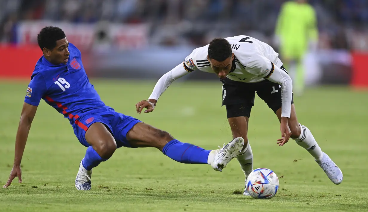 Pemain Inggris, Jude Bellingham berebut bola dengan pemain Jerman, Jamal Musala pada pertandingan Grup A3 UEFA Nations League di Allianz Arena, Munich, Rabu (8/6/2022). Inggris bermain imbang dengan Jerman 1-1. (AP Photo/Markus Ulmer)