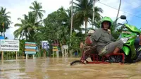 Warga menggunakan jasa angkutan becak untuk melintasi jalan lintas Calang-Meulaboh yang tergenang banjir luapan sungai Teunom di Desa Gampong Baro Kecamatan Teunom Kabupaten Aceh Jaya. (Antara)