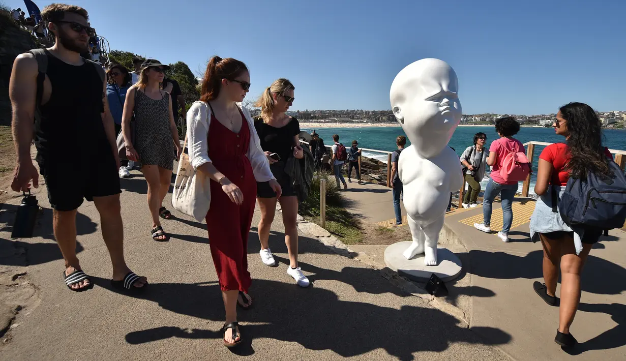 Pengunjung berjalan dekat patung berjudul Niemand karya Victor Fresco saat pameran Sculpture by the Sea di Sydney, Australia, Jumat (19/10). Saat acara dimulai, sekitar 12 hingga 15 patung belum terpasang karena hujan terus berlangsung. (PETER PARKS/AFP)