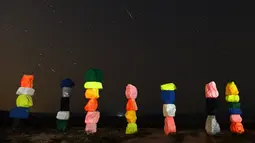 Meteor Perseid melintasi langit di atas instalasi seni "Seven Magic Mountains" dekat Jean, Nevada (13/8). Instalasi seni Seven Magic Mountains terdiri dari tujuh pilar batu-batu berwarna yang ditumpuk lebih dari 30 kaki tingginya. (AFP Photo/Ethan Miller)