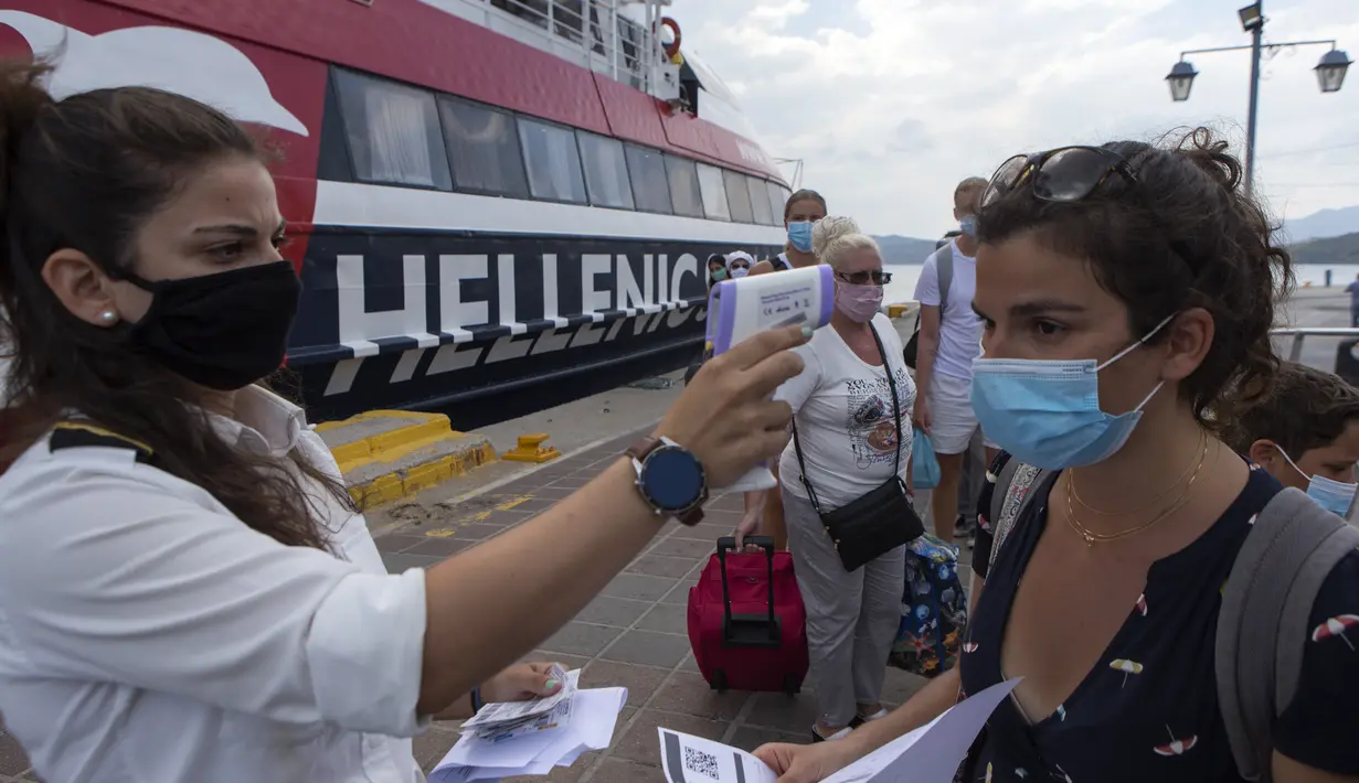 Petugas pelabuhan memeriksa suhu tubuh seorang penumpang di Pulau Poros, Yunani (7/8/2020). Terus bertambahnya jumlah kasus terkonfirmasi coronavirus di beberapa wilayah Yunani memaksa pihak berwenang memberlakukan jam malam pertama selama musim pariwisata di Pulau Poros. (Xinhua/Marios Lolos)