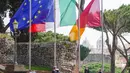 Bendera nasional Italia dikibarkan setengah tiang saat mengheningkan cipta selama satu menit di Capitol Hill Roma, Selasa (31/3/2020). Italia mengheningkan cipta dan menaikkan bendera setengah tiang untuk memberikan penghormatan bagi para korban virus corona dan keluarga mereka (AP/Andrew Medichini)