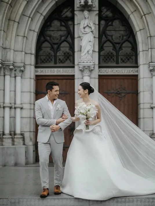 Jonatan sendiri memilih setelan jas dan celana panjang berwarna abu-abu. Kemeja putih dan bunga yang disematkan di kantong dadanya membuat penampilan Jonatan semakin luar biasa. [Foto: Instagram/thebridestory]