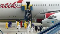 Sejumlah Warga Negara Indonesia (WNI) yang dievakuasi dari Wuhan, China keluar dari pesawat  Batik Air di bandara internasional Hang Nadim, Batam, Minggu (2/2/2020). Sebanyak 245 WNI di Wuhan akan dievakuasi ke Indonesia terkait merebaknya virus corona di kota tersebut. (AFP/Ricky Prakoso)