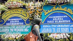 Seorang warga berjalan di deretan karangan bunga ucapan bela sungkawa atas meninggalnya putra Menteri Susi, almarhum Panji Hilmansyah di luar kediaman Menteri Kelautan dan Perikanan tersebut, Jakarta, Senin (18/1/2016). (Liputan6.com/Helmi Afandi)