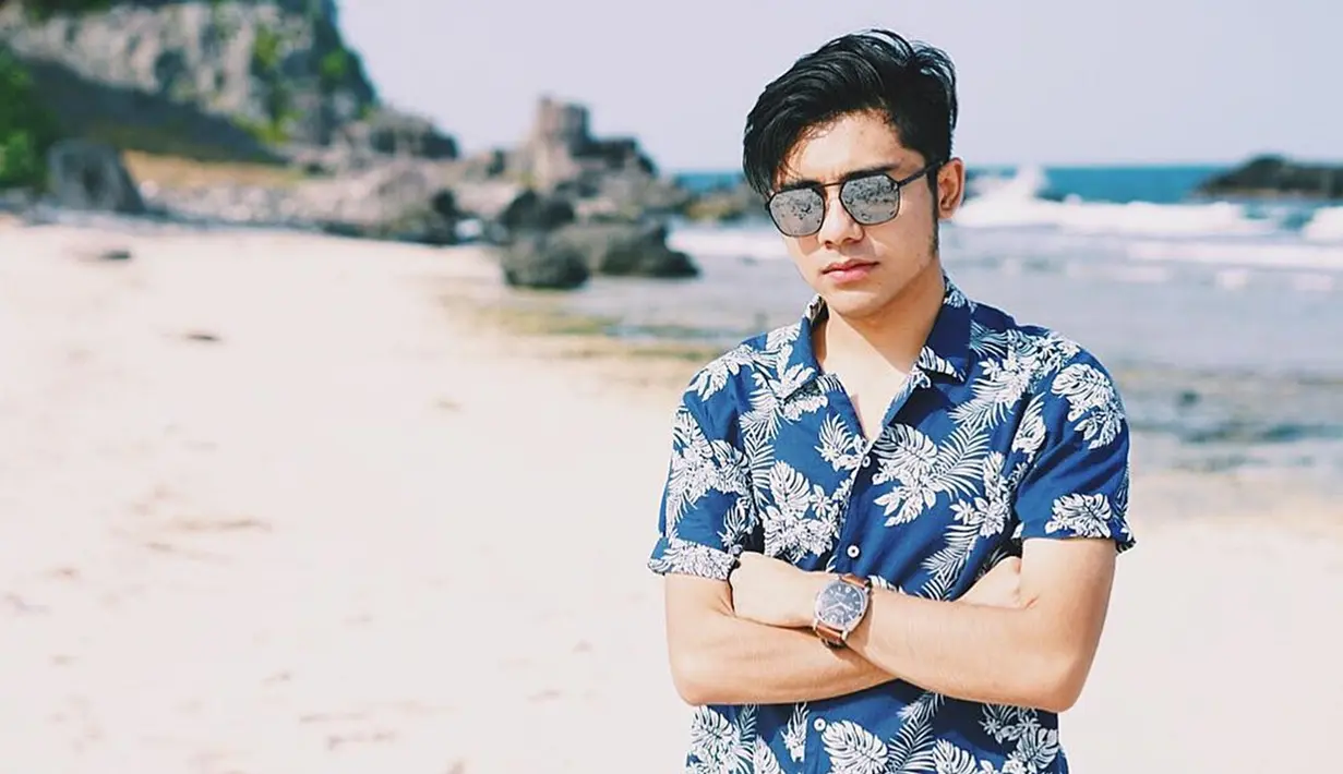 Saat pergi berlibur di pantai, kacamata menjadi fashion item yang tak boleh terlewatkan bagi bintang sinetron ini. Berbusana baju pantai dengan kacamata hitam, membuat penampilan Riza terlihat lebih maskulin. (Liputan6.com/IG/@rizasyah_14)