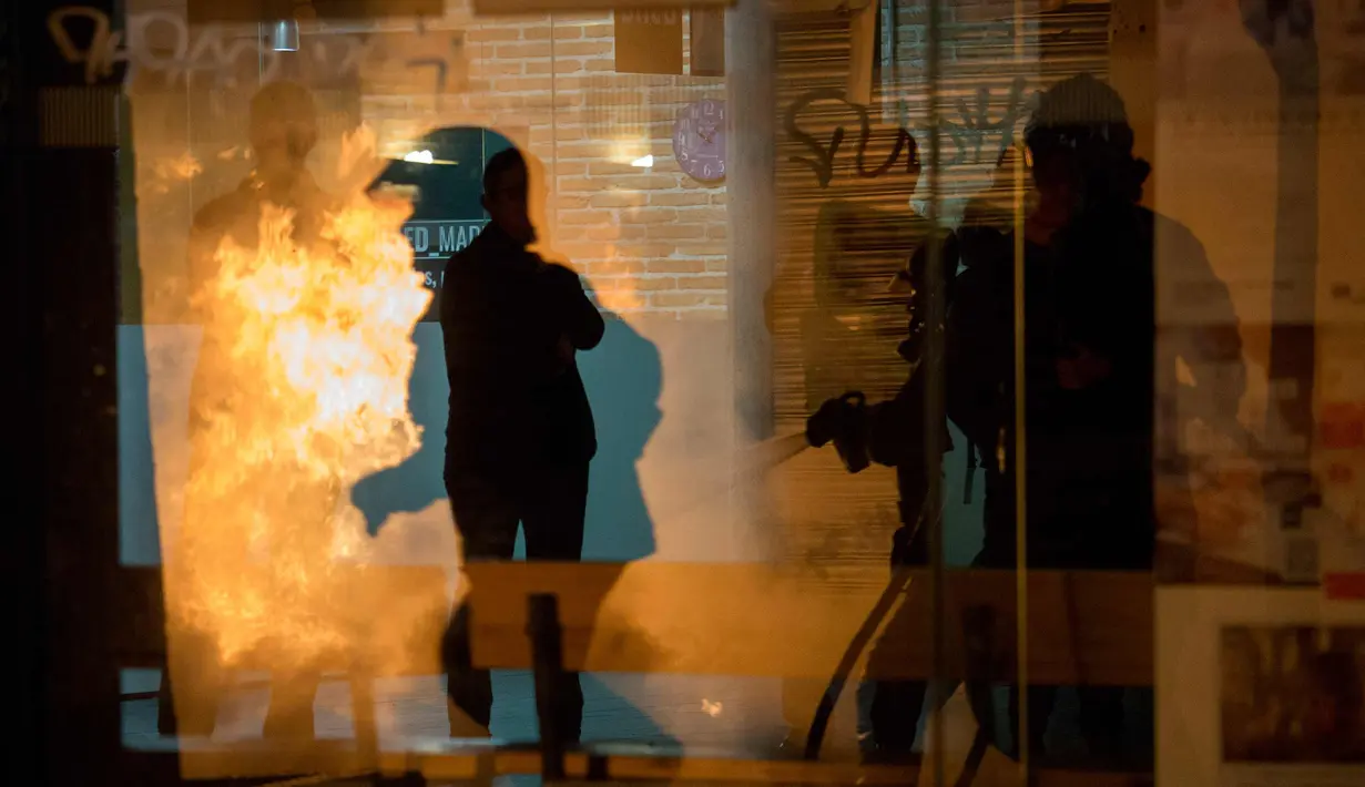 Petugas polisi saat terlibat bentrok dengan imigran di Madrid, Spanyol, Kamis (15/3). Bentrokan berawal dari aksi protes imigran atas meninggalnya seorang pedagang jalanan asal Senegal. (AFP Photo/Olmo Calvo)