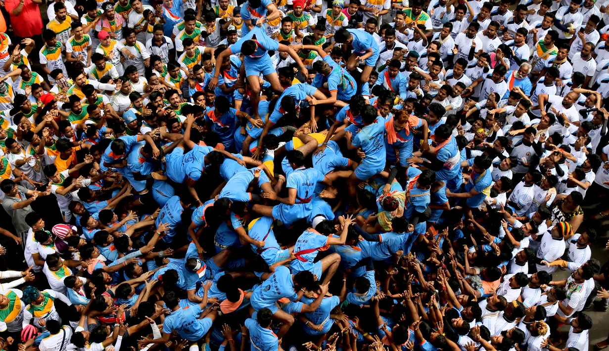 Pemuda India membentuk piramida manusia untuk memecahkan pot berisikan semacam susu dalam perayaan Festival Janmashtami di Mumbai, Senin (3/9). Para remaja mendaki ke tingkat paling atas tanpa alat keamanan sama sekali. (AP/Rafiq Maqbool)