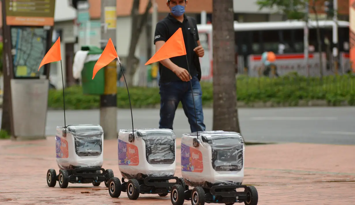 Robot pengiriman berjalan menyusuri jalan di Medellin, Kolombia, Selasa (21/4/2020). Robot yang bergerak dengan empat roda dengan bendera oranye di antena, membawa kiriman hingga berukuran 35 sentimeter persegi dan digunakan mengantar pesanan restoran dengan pembayaran digital. (AP/Luis Benavides)