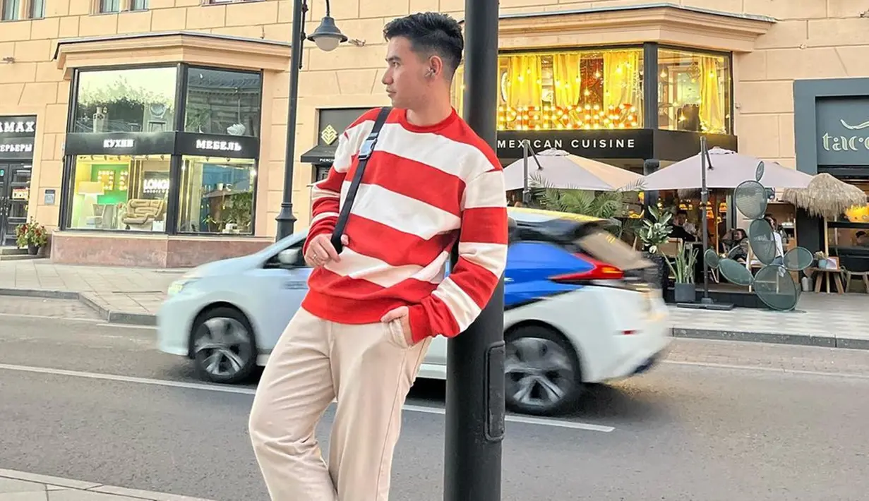 Hari Putra memang pandai memadupadankan busana, termasuk saat liburan. Dengan gaya kasual, pria kelahiran Jambi itu tampak mengenakan kaus garis-garis berwarna merah putih yang dipadukan dengan celana krem. (Liputan6.com/IG/@hariiputraa_lida2020)