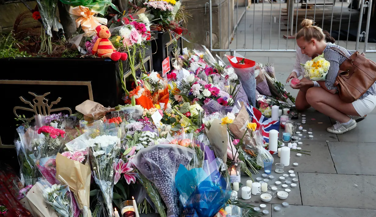Bunga dan lilin diletakan setelah serangan bunuh diri di sebuah konser Ariana Grande di Albert Square, Manchester, Inggris, (23/5). Kepolisian Inggris menetapkan pelaku bom diri di konser Ariana Grande bernama Salman Abedi. (AP Photo/Kirsty Wigglesworth)