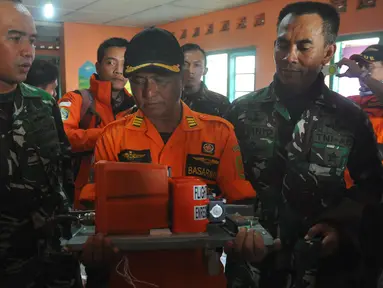 Petugas dari Basarnas memegang sebuah kotak hitam atau Black Box dari helikopter Basarnas yang jatuh di Temanggung, Jawa Tengah (3/7). Helikopter yang membawa 8 orang tersebut jatuh saat perjalanan menuju lokasi letusan kawah Dieng. (AFP Photo/STR)