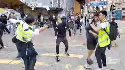 Polisi (kiri) bersiap untuk menembak seorang demonstran prodemokrasi (tengah) saat terjadi protes di Distrik Sai Wan Ho, Hong Kong, Senin (11/11/2019). Polisi menembak seorang pria bertopeng saat tengah berupaya menahan seorang demonstran. (Cupid Producer via AP)