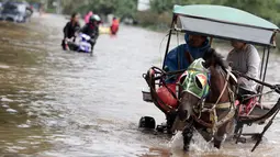 Hujan yang turun sejak Minggu (8/2) lalu, mengakibatkan kawasan Kelapa Gading, Jakarta terendam banjir. Pejalan kaki memilih naik delman untuk menembus banjir di kawasan tersebut, Selasa (10/2/2015). (Liputan6.com/Faizal Fanani)