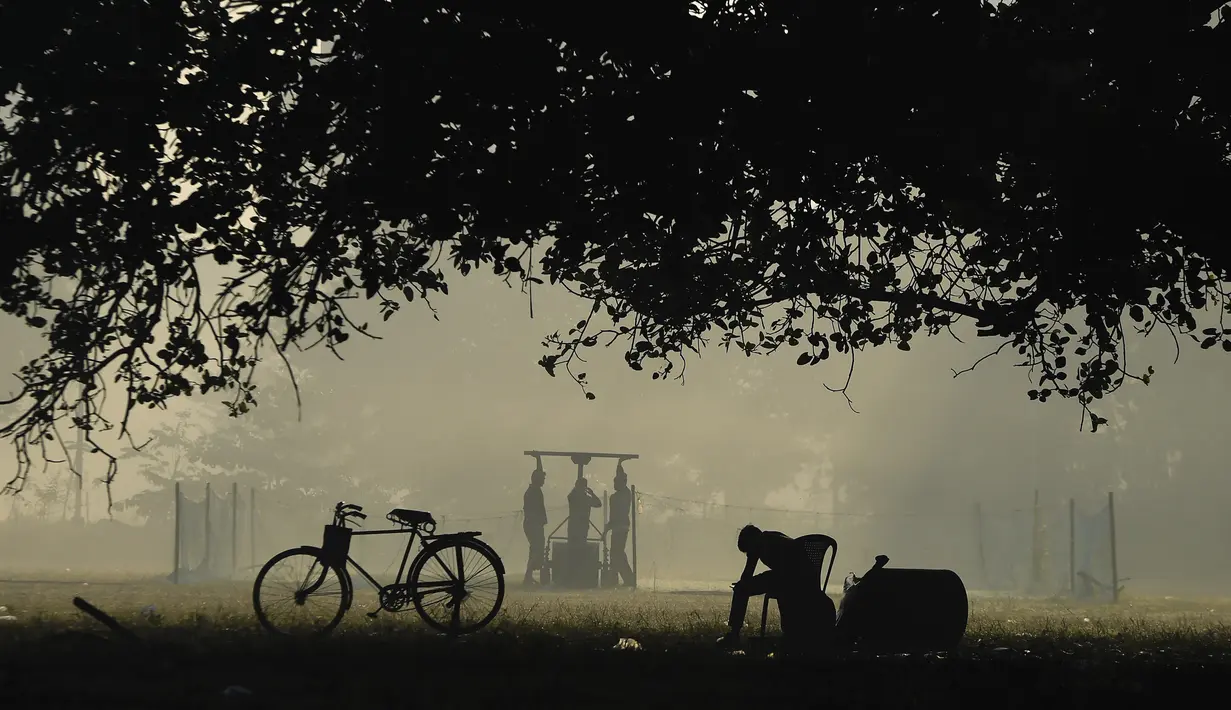 Seorang petugas lapangan melempar bola kriket pada pagi berkabut di taman Maidan di Kolkata (29/11/2019). Maidan  merupakan taman bandar terbesar di Kolkata di negeri dalam India di Bengal Barat. (AFP Photo/Dibyangshu Sarkar)