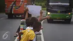 Sejumlah anak menggunakan kertas meminta bunyi klakson telolet ke bus yang lewat di jalan raya A Yani Surakarta, Solo, Kamis (22/12). Fenomena ini mendunia setelah beberapa artis dan tokoh terkenal dunia berkomentar di media sosial. (Liputan6.com/Gholib)
