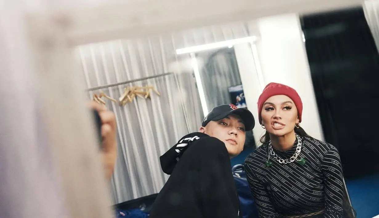 Dalam outfit hitam, Agnez memakai set Balenciaga dengan kalung rantai plus topi rajut andalannya. Dan Adam memakai hoodie dan baseball cap. (Foto: Instagram @adamrxsydi)