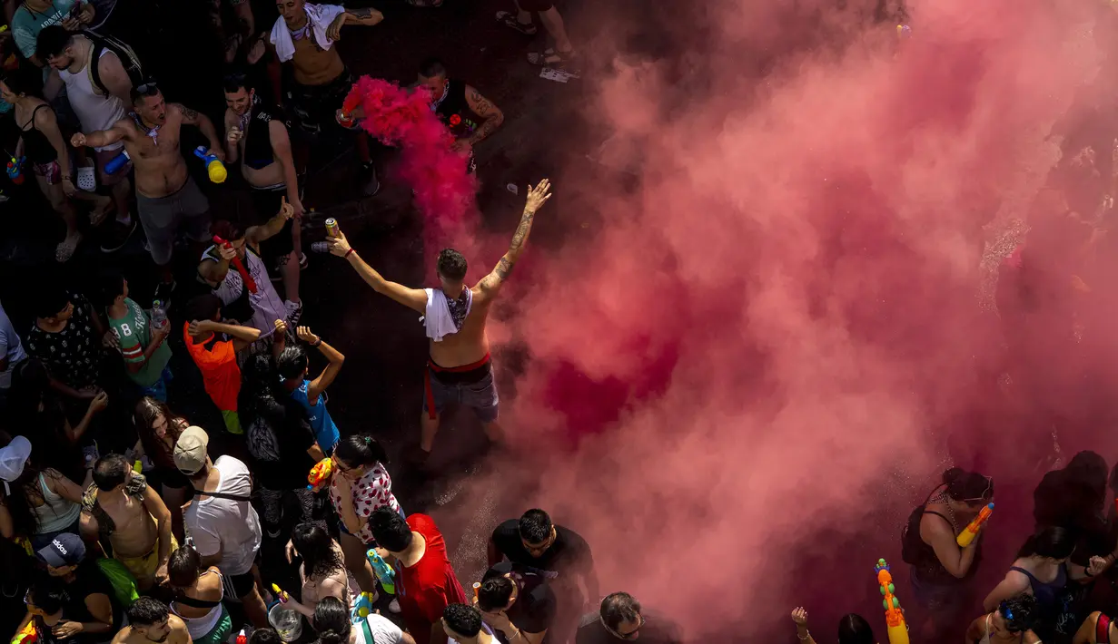 Orang-orang mengikuti perang air tahunan di jalan-jalan lingkungan Vallecas, Madrid, Spanyol, 17 Juli 2022. Banyak peserta yang tiba-tiba mandi di tengah jalan selama perang air ini. (AP Photo/Manu Fernandez)