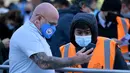 Penonton dengan memakai masker memberikan bukti tes virus corona negatif kepada petugas sebelum pertandingan dimulai. (Foto: AFP/Pool/Ben Stansall)