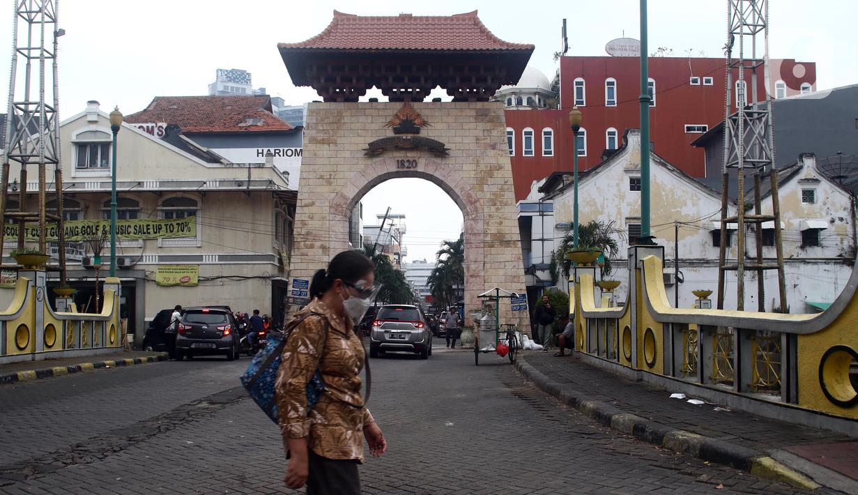 Warga berjalan di depan gerbang kawasan Pasar Baru, Jakarta, Kamis (22/9/2022). Pemerintah Provinsi (Pemprov) DKI Jakarta menetapkan Kompleks Jalan Pasar Baru sebagai Kawasan Cagar Budaya pada Rabu (21/9/2022). (Liputan6.com/Helmi Fithriansyah)