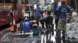 Petugas harian lepas (PHL) dari Sudin Sumber Daya Air dikerahkan untuk membersihkan saluran di Jalan Gatot Subroto, Jakarta, Jumat (10/3). Pembersihan dilakukan karena di kawasan ini banjir selalu datang saat hujan turun. (Liputan6.com/Yoppy Renato)