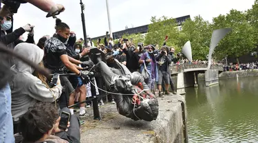 Demonstran melempar patung pedagang budak Edward Colston ke Pelabuhan Bristol saat protes Black Lives Matter di Bristol, Inggris, Minggu (7/6/2020). Aksi tersebut dilakukan sebagai bentuk protes atas kematian George Floyd saat ditangkap oleh polisi di Amerika Serikat. (Ben Birchall/PA via AP)