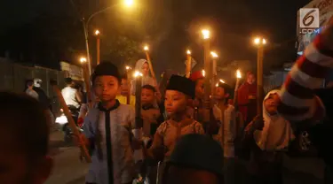 Sejumlah anak berpawai sambil membawa obor di Jalan Tengah, Batu Ampar, Jakarta Timur, Sabtu (24/6). Kegiatan tersebut dalam rangka menyambut Idul Fitri 1 Syawal 1438 Hijriyah. (Liputan6.com/Angga Yuniar)